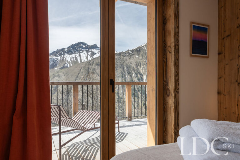 Chalet Aurea bedroom with doors opening onto a balcony overlooking the mountains