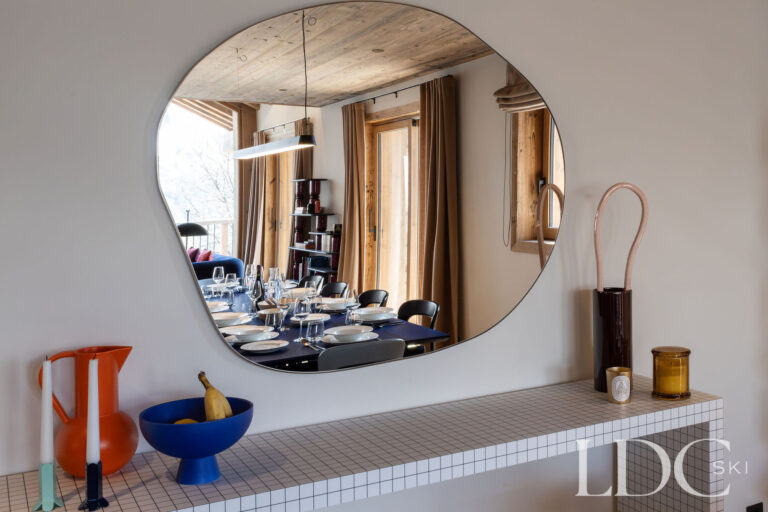 Chalet Aurea dining area reflected in a circular wall mirror