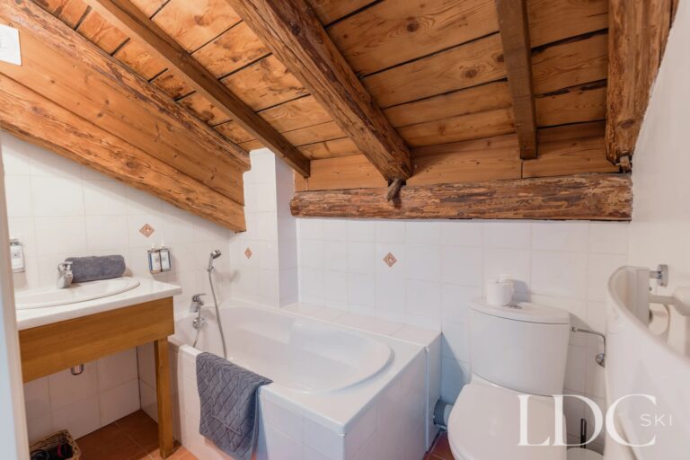Bathroom with bath beneath exposed timber beams at Chalet Aux Joux in Morzine
