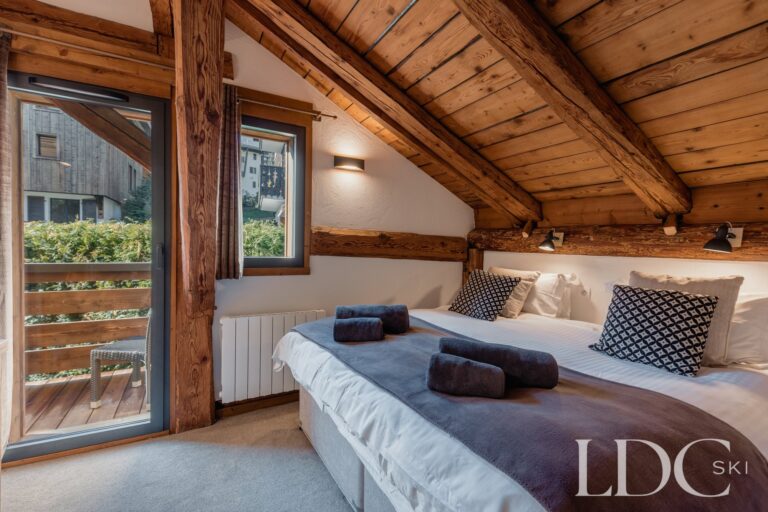 Double bedroom beneath a traditional timber ceiling at Chalet Aux Joux in Morzine