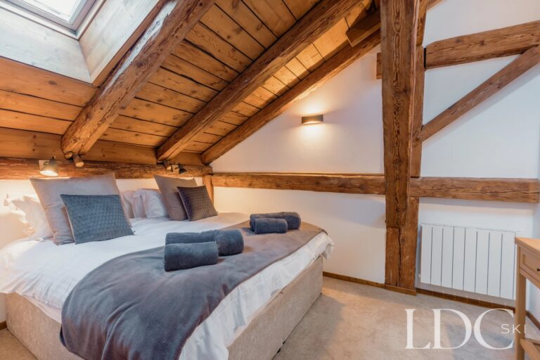 Double bedroom with exposed timber beams at Chalet Aux Joux