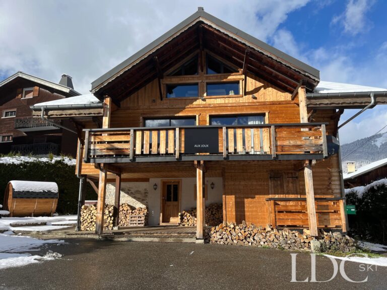 Snowy exterior of Chalet Aux Joux with mountains behind in Morzine