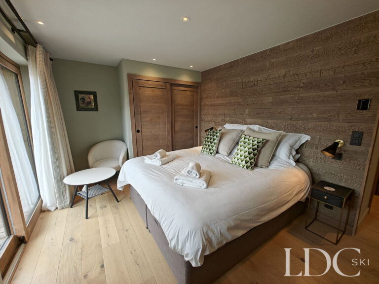 Bright bedroom with balcony access and snowy mountain views at Chalet Chardon