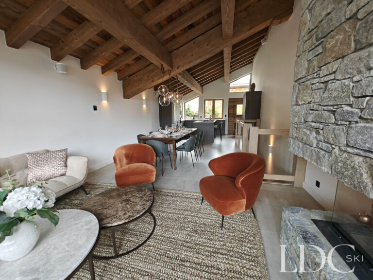 Open-plan lounge and dining area with exposed beams and mountain views at Chalet Chardon