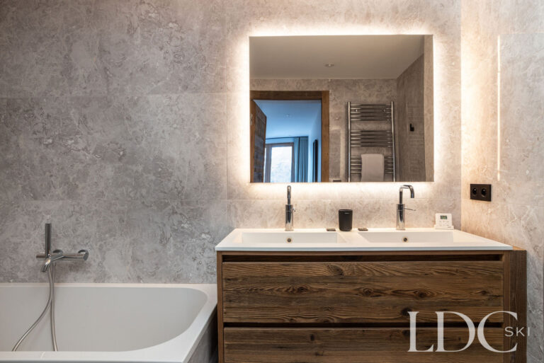 Contemporary bathroom with bath, double vanity and illuminated mirror at Chalet de Beauvoir