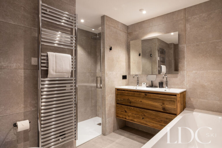Modern bathroom with bath, walk-in shower and wooden vanity at Chalet de Beauvoir