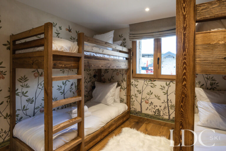Bunk bedroom at Chalet de Beauvoir with handcrafted wooden bunk beds and decorative botanical wallpaper