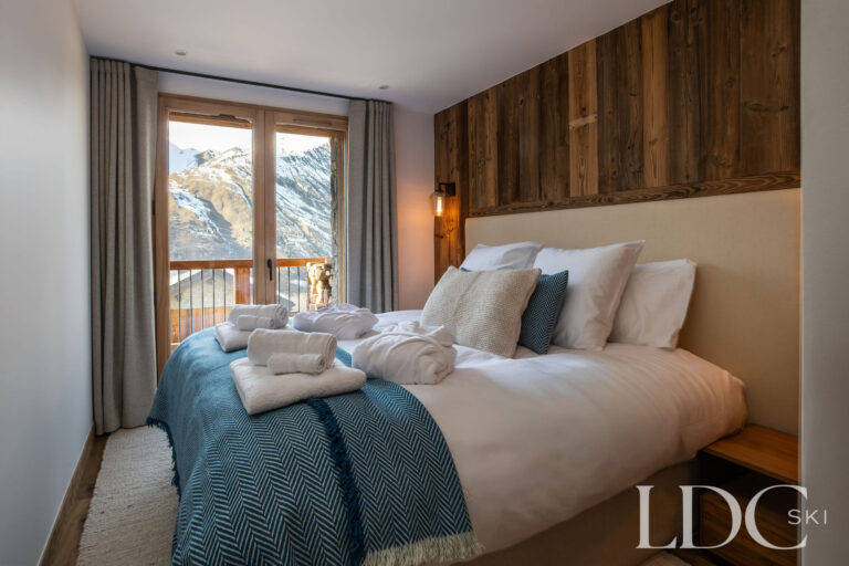 Double bedroom at Chalet de Beauvoir with warm wood panelling and mountain views from the window