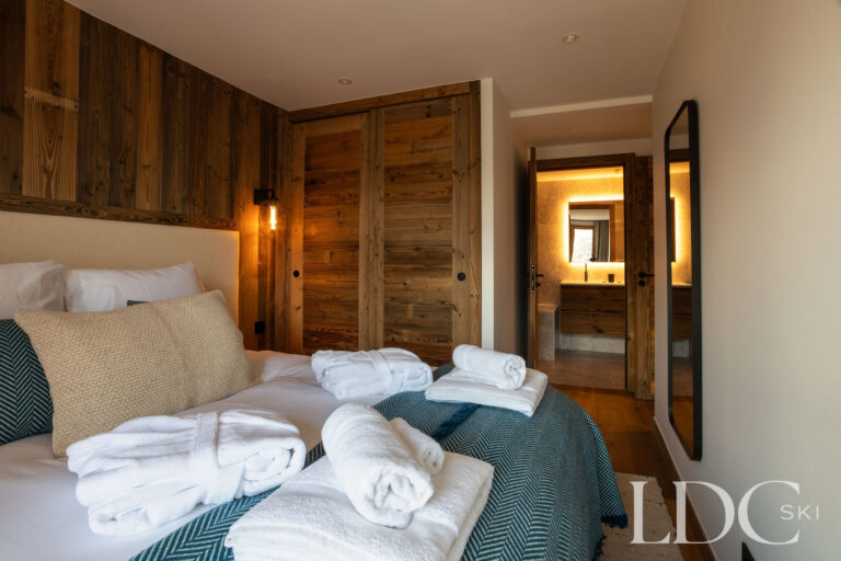 Double bedroom at Chalet de Beauvoir with wood-panelled walls and adjoining en-suite bathroom