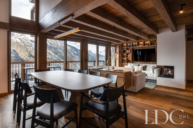 Open-plan dining and living area at Chalet de Beauvoir with fireplace and panoramic mountain views