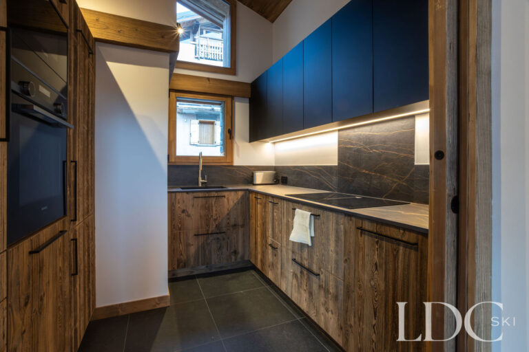 Fully equipped kitchen at Chalet de Beauvoir with wood cabinetry, integrated oven and modern worktops