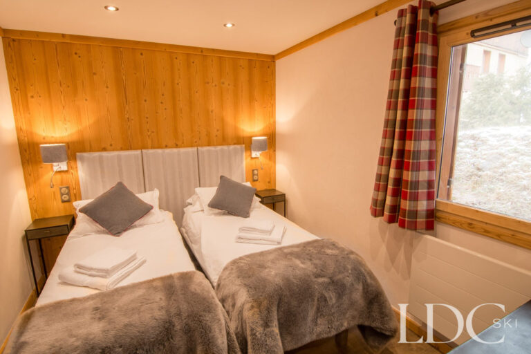 Twin bedroom at Chalet Astragle with timber panelling and alpine-style furnishings