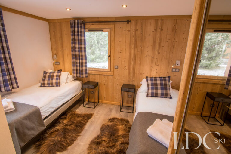 Twin bedroom at Chalet Astragle with two single beds and traditional timber panelling