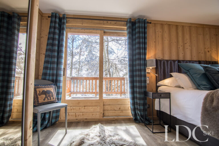 Double bedroom at Chalet Astragle with doors opening onto a balcony