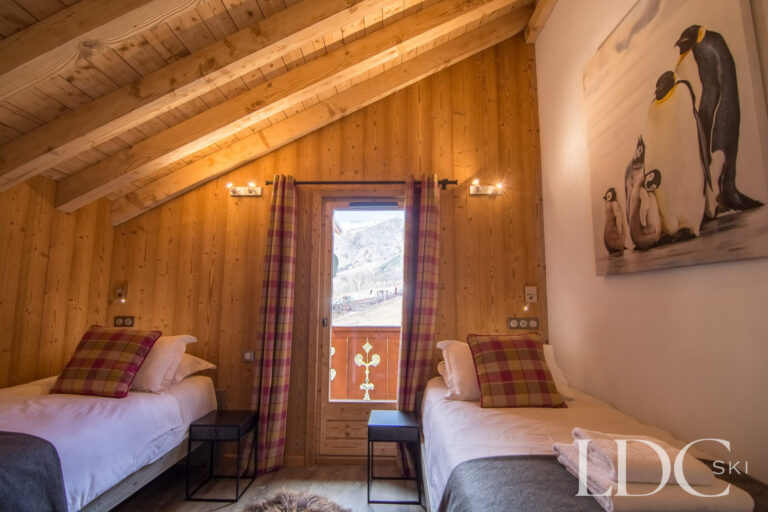 Twin bedroom at Chalet Astragle beneath a vaulted timber ceiling