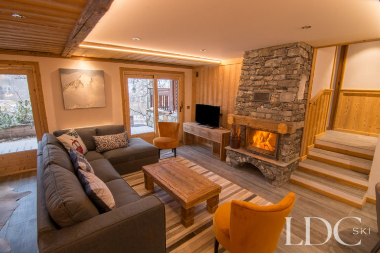 Lounge at Chalet Astragle with comfortable seating and log fire set into a stone fireplace