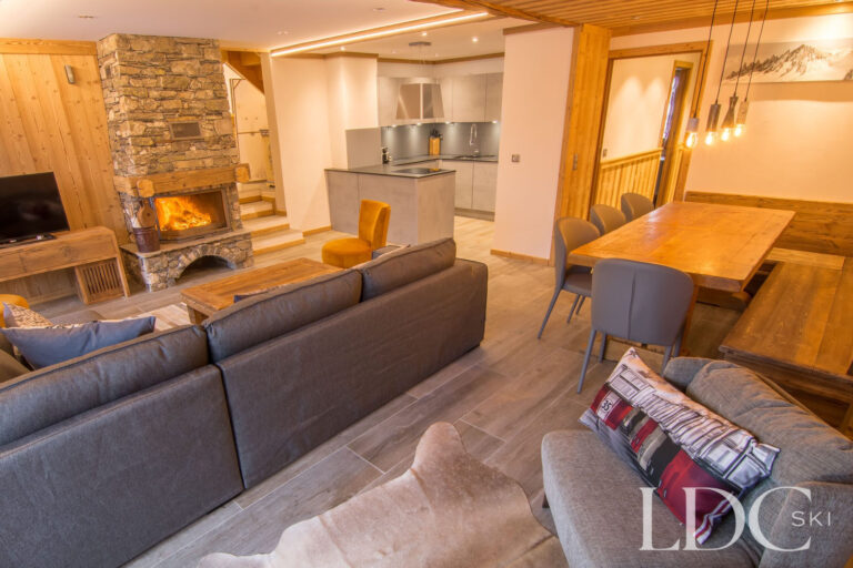 Open-plan lounge and dining area at Chalet Astragle with stone fireplace and timber interiors