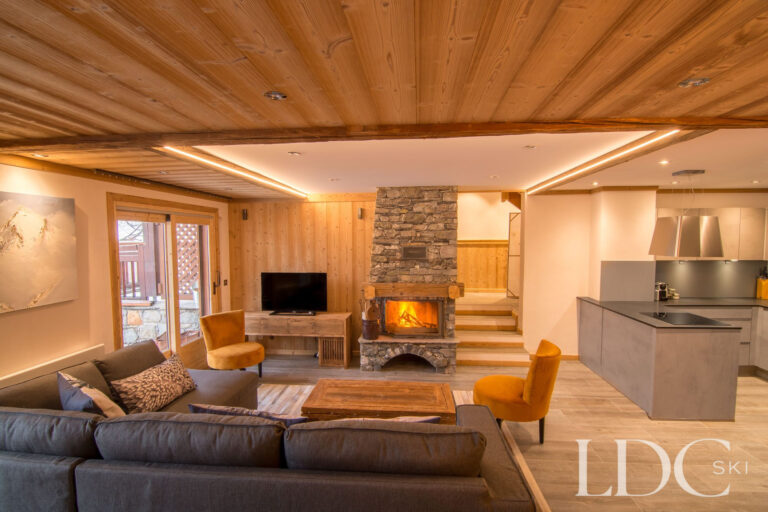 Spacious living area at Chalet Astragle with sofas, log fire and open-plan kitchen