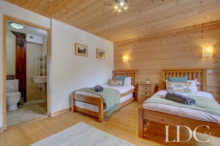 Chalet Jouet twin bedroom with timber walls and ensuite shower room