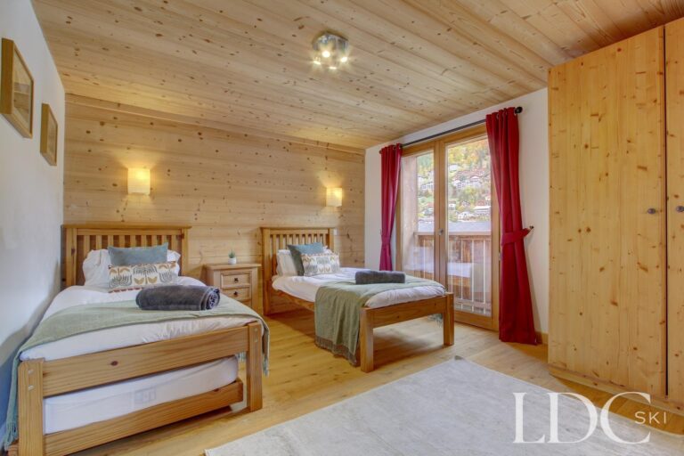 Chalet Jouet spacious twin bedroom with timber walls and balcony access