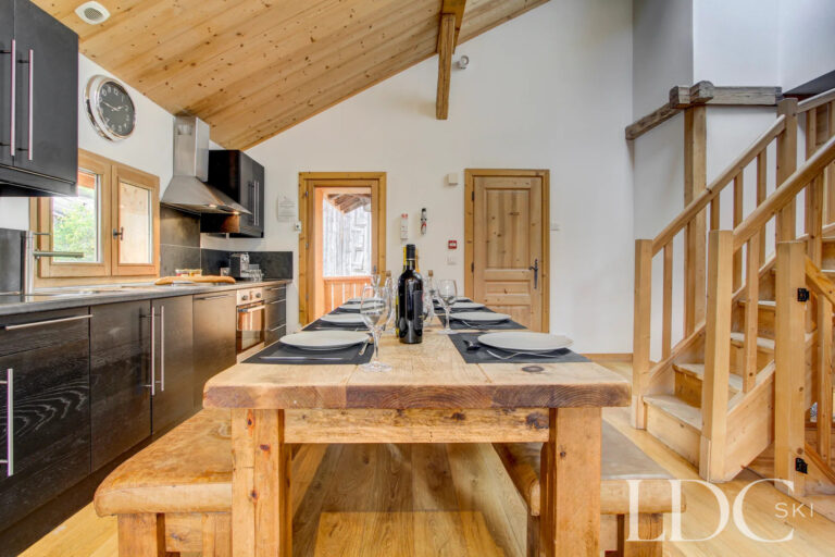 Chalet Jouet dining area with large timber table and open-plan kitchen