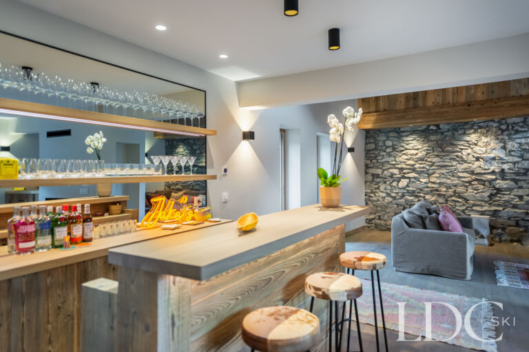 Chalet La Fermette bar area with stone feature wall, timber counter and stools
