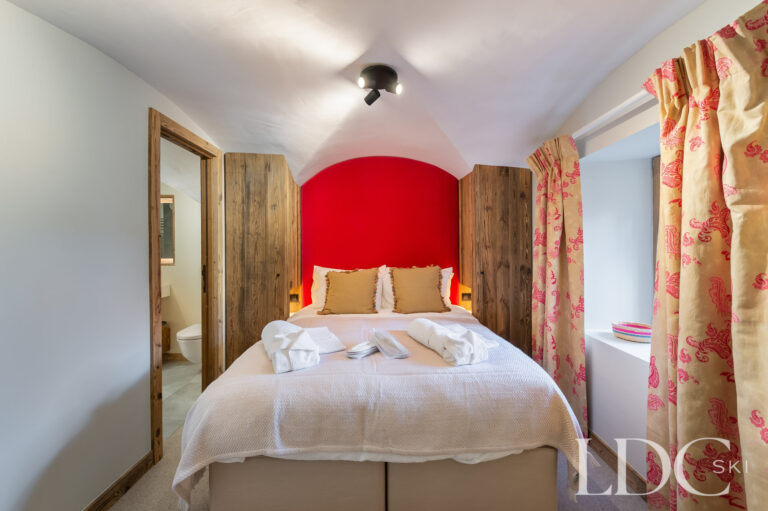 Double bedroom at Chalet La Fermette with red feature wall and patterned curtains