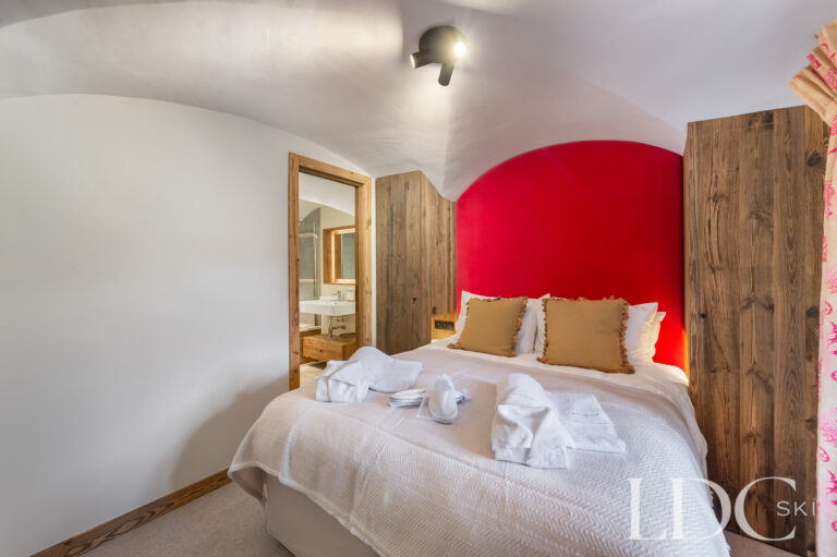 Double bedroom at Chalet La Fermette with red feature wall and timber wardrobe