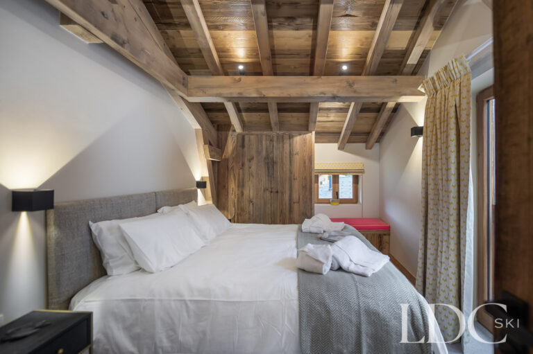 Double bedroom at Chalet La Fermette beneath a vaulted timber ceiling