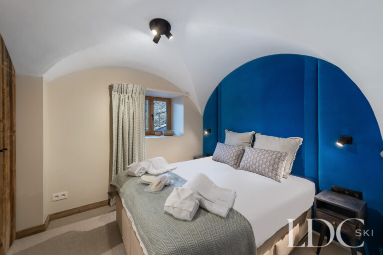 Double bedroom at Chalet La Fermette with blue feature wall and alpine-style furnishings