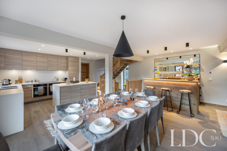Open-plan dining area at Chalet La Fermette with bar and kitchen beyond