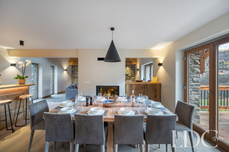 Dining area at Chalet La Fermette with large table and doors opening towards the balcony