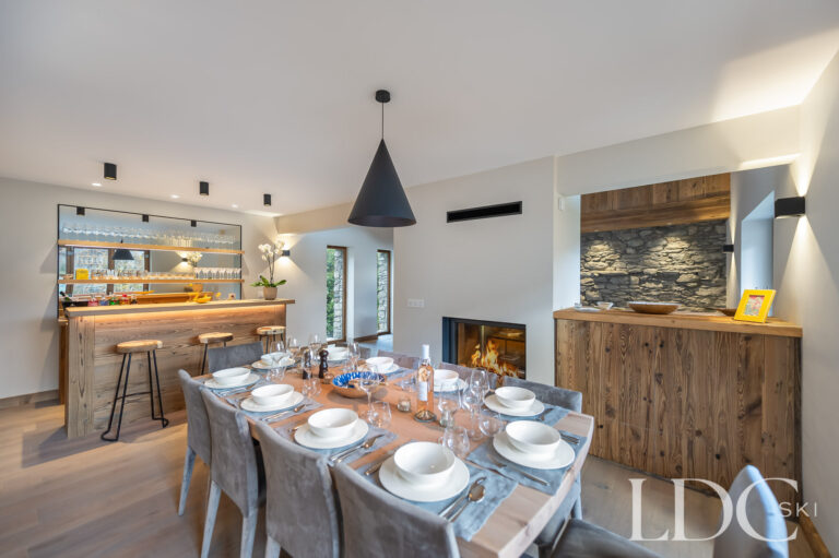 Chalet La Fermette dining area with contemporary fireplace and bar beyond