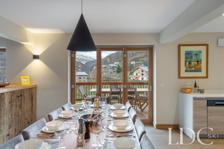 Dining area at Chalet La Fermette with windows overlooking St Martin de Belleville
