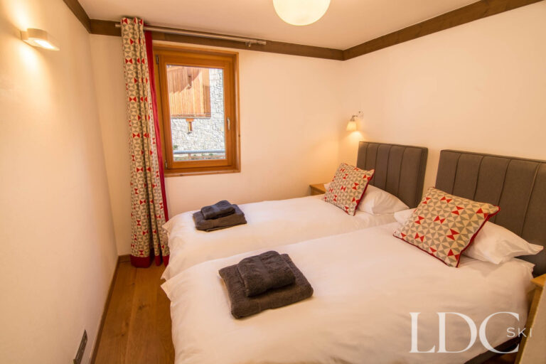 Twin bedroom at Chalet Le Pic Blanc with two single beds and alpine-style furnishings