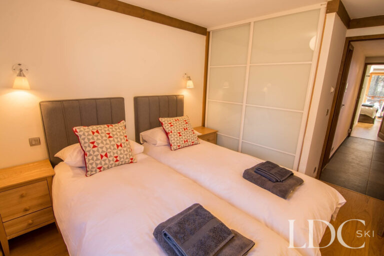 Twin bedroom at Chalet Le Pic Blanc with fitted wardrobe and bedside lighting