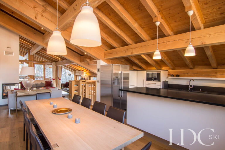 Spacious dining and kitchen area at Chalet Le Pic Blanc beneath exposed timber beams