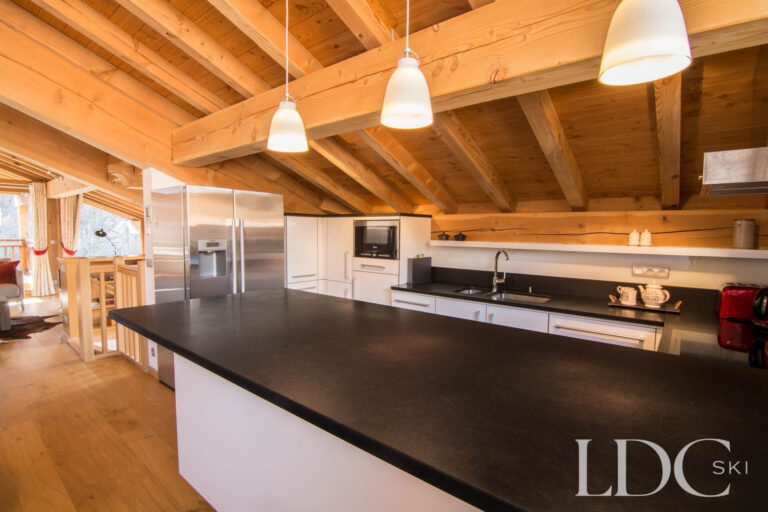 Open-plan kitchen at Chalet Le Pic Blanc with island and exposed timber ceiling