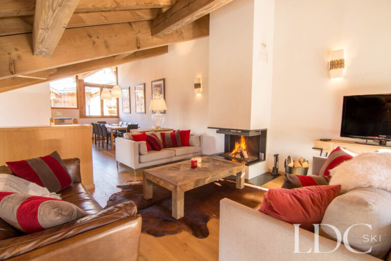 Open-plan living area at Chalet Le Pic Blanc with lounge, fireplace and dining area