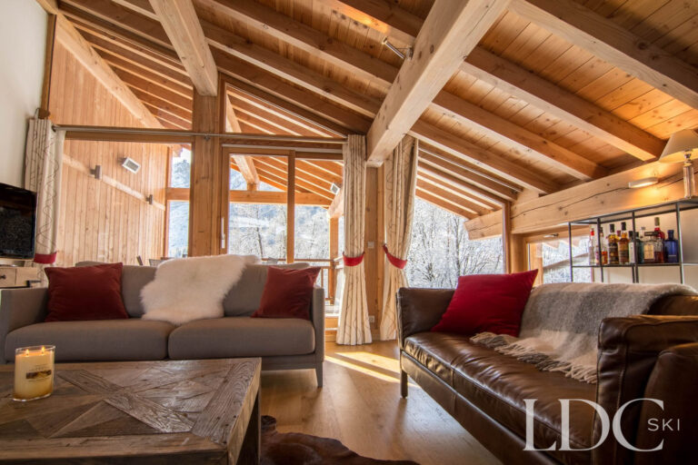 Alpine-style lounge at Chalet Le Pic Blanc with sofas, exposed beams and large windows