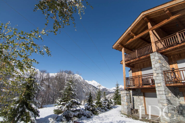 Timber and stone exterior of Chalet Le Pic Blanc surrounded by snow and mountain scenery
