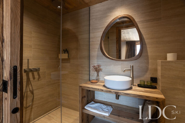 En-suite shower room at Chalet Lenafaju with walk-in shower, round mirror and wooden vanity