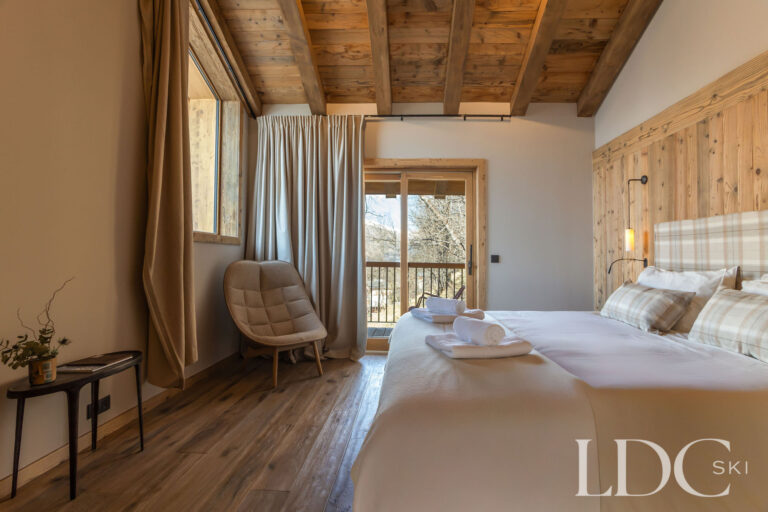 Double bedroom at Chalet Lenafaju with timber ceiling, wood panelling and balcony doors