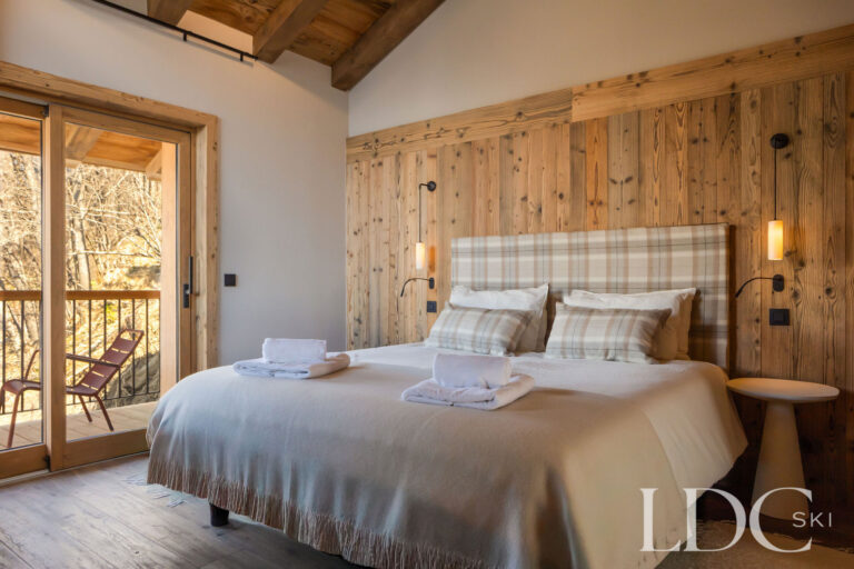 Double bedroom at Chalet Lenafaju with wood-panelled walls, balcony access and mountain views