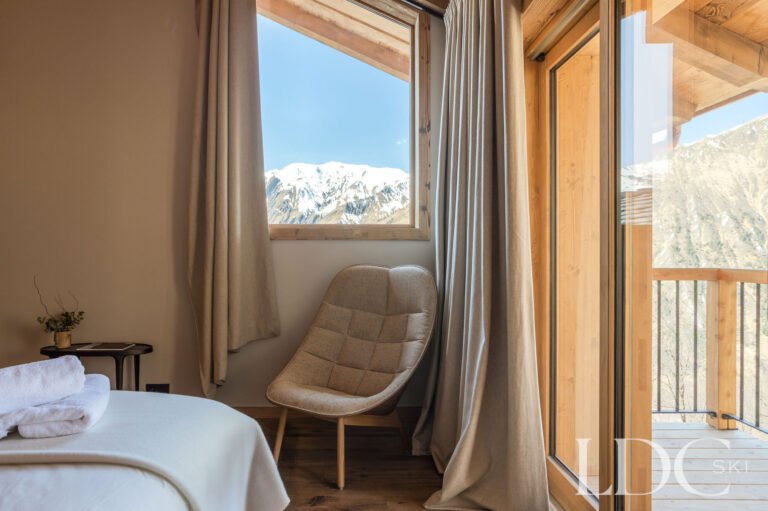 Bedroom at Chalet Lenafaju with armchair, balcony doors and views towards the mountains