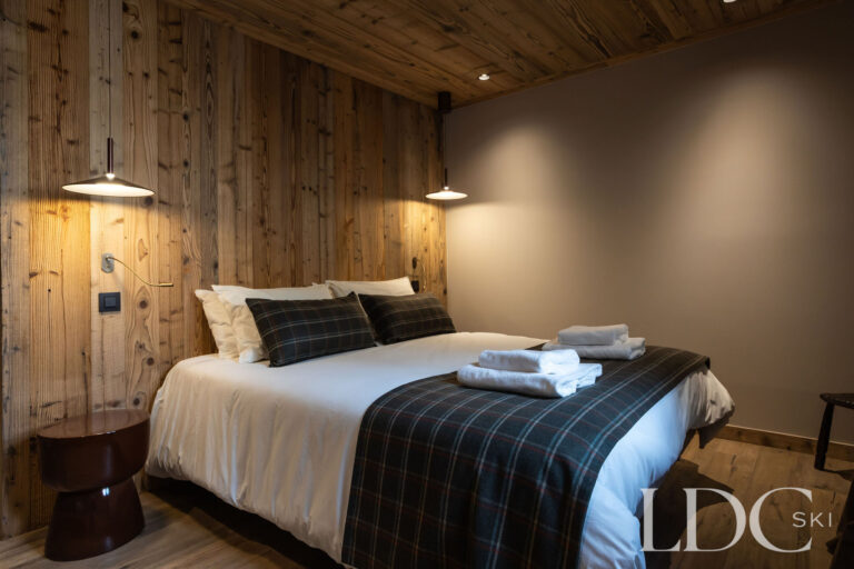 Double bedroom at Chalet Lenafaju with timber walls, soft lighting and contemporary alpine décor