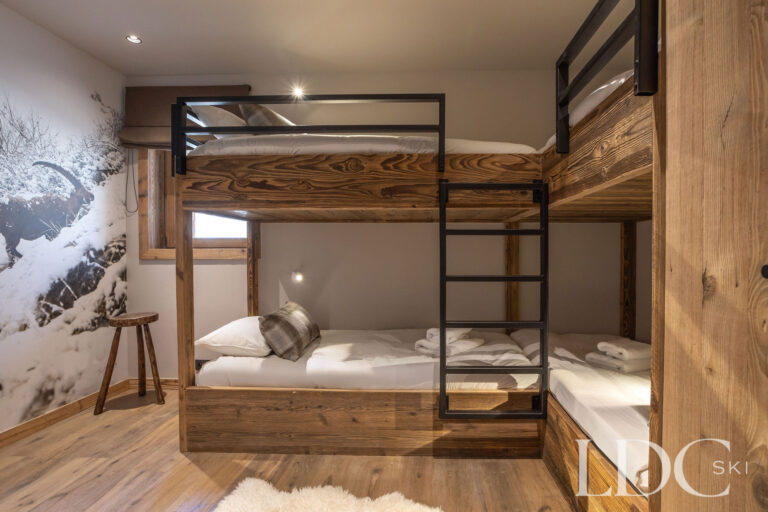 Bunk bedroom at Chalet Lenafaju with built-in wooden bunk beds and mountain-themed wall decoration
