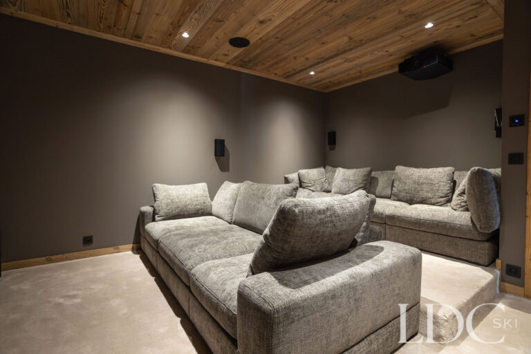 Private cinema room at Chalet Lenafaju with large screen and comfortable sofa seating
