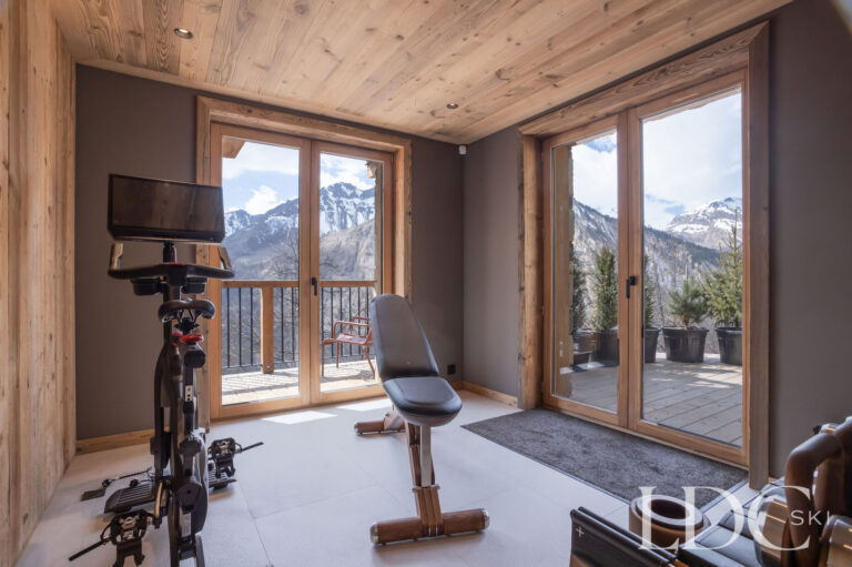Private gym at Chalet Lenafaju with exercise bike and floor-to-ceiling mountain views