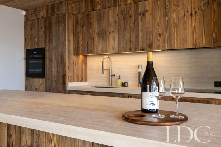 Kitchen at Chalet Lenafaju with timber breakfast bar, wine and contemporary alpine finishes